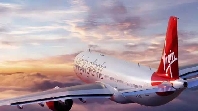 Virgin Atlantic aircraft flying above the clouds at sunset